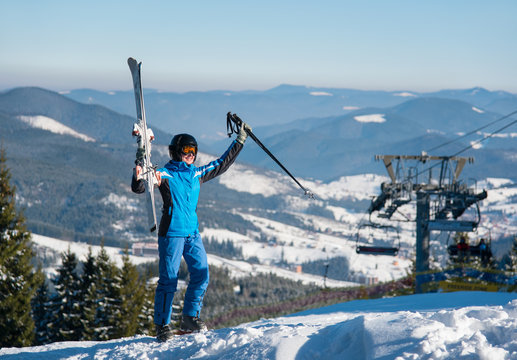Full length shot of a happy woman posing with her skis on top of the mountains celebrating success holding her equipment up in the air, smiling joyfully copyspace. Bukovel