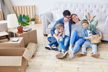 Fototapeta na wymiar Full length portrait of loving young family gathered together in living room of new apartment and sharing ideas concerning interior design, cute little boy holding houseplant in hands