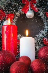 Christmas red balls, candles, spruce branches, wreath and snowflakes on a dark background Decoration for a New Year's holiday with a copy space