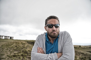 Man in sunglasses with beard on serious face fold hands