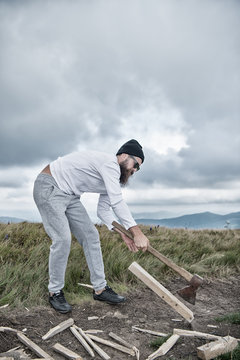 Lumberjack bearded man chop wood with axe on mountain landscape