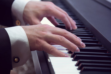 Obraz premium man's hands playing on a piano at the concert