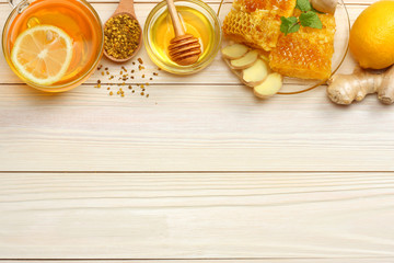 Obraz na płótnie Canvas healthy background. honey, honeycomb, lemon, tea, ginger on white wooden table. Top view with copy space