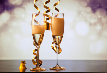 two champagne glasses with ribbons against holiday lights and fireworks - New Year celebrations