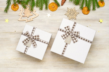 Christmas background. Two gift box with bow of different sizes. The branches of fir, dried orange, star foil, fir cone, wooden toys in the shape of Christmas trees and snowflakes