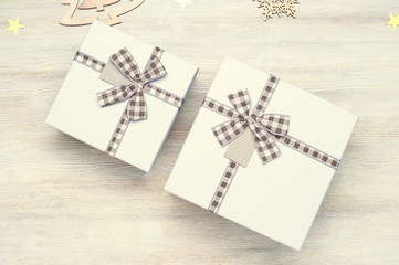 Vintage Christmas background. Two gift box with bow of different sizes. Wooden toys in the shape of Christmas trees and snowflakes on a white wooden background