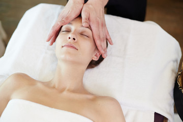 Fototapeta na wymiar Above view portrait of young woman enjoying face lifting massage lying with eyes closed in SPA center and relaxing