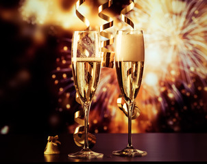 two champagne glasses with ribbons against holiday lights and fireworks - New Year celebrations