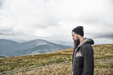 Hipster with serious face at mountains.