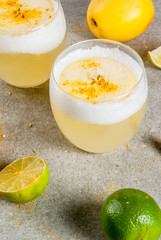 Peruvian, Mexican, Chilean traditional drink pisco sour liqueur, with fresh lime, on gray stone table, copy space