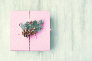 Vintage pink gift box decorated with cedar cones and fir Vetco light wooden background. The view from the top.