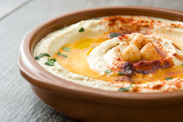 Chickpea hummus in bowl on wooden table.