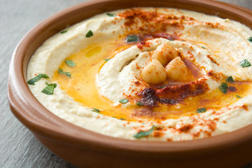 Chickpea hummus in bowl on wooden table.