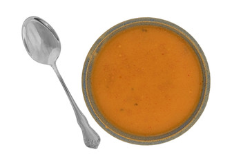 Top view of a serving of salmon bisque soup in an old stoneware bowl with a spoon to the side isolated on a white background.
