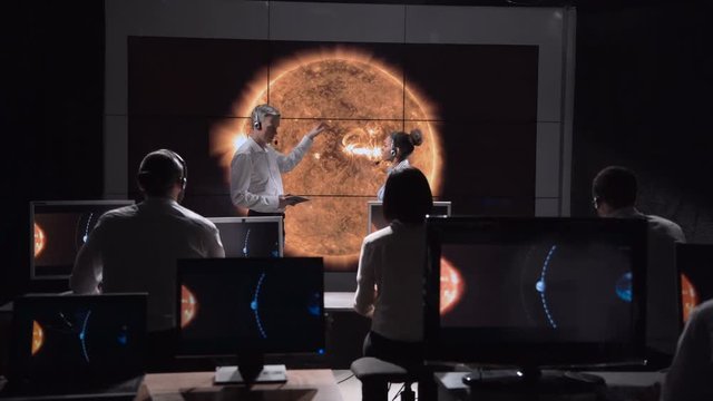 Two scientists discuss the trajectory of the shadow of the solar eclipse moving along the surface of the Earth. Elements of this image furnished by NASA.