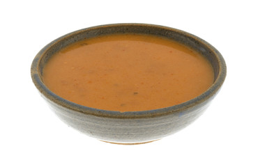 A serving of salmon bisque soup in an old stoneware bowl isolated on a white background.