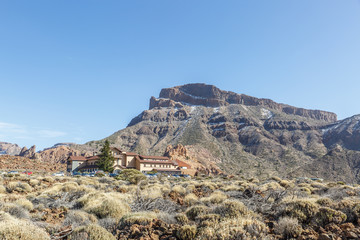 Landscape of an arid area with a building and a big mountain in the background