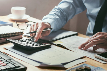 businessman working on desk office with using a calculator to calculate the numbers, finance accounting concept - obrazy, fototapety, plakaty