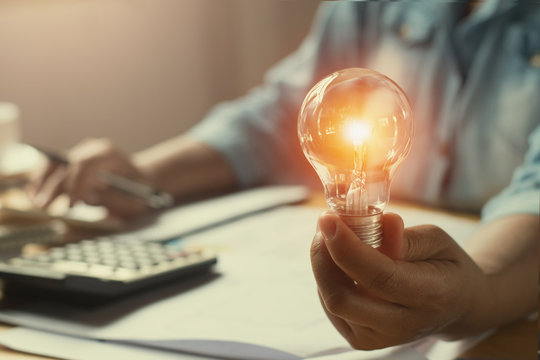 hand woman accountant holding light bulb, new idea with innovation concept