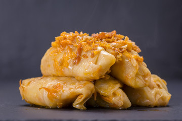 Ukrainian dishes - homemade stuffed cabbage rolls with rice and meat in tomato sauce on a black slate background