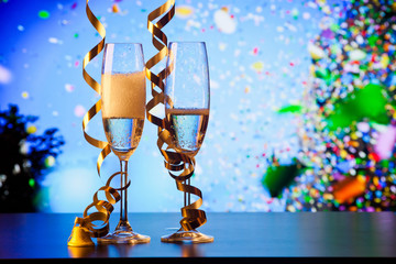 Fototapeta na wymiar two champagne glasses with ribbons and falling confetti - New Year celebrations