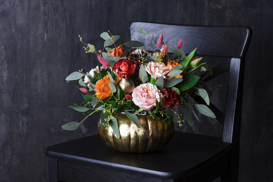 Autumn floral bouquet in punpkin vase on black chair