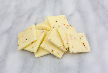 A small pile of fresh pepper jack cheese on a gray marble cutting board.