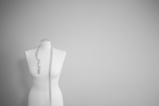 black and white picture of tailor dummy with measuring tape 