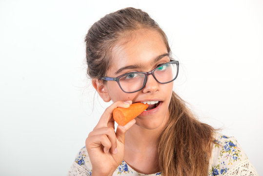 girl with carrot. Vitamins for teenagers. Vegetabl for healthy eating of children. Positive weight loss. Portrait of girl with carrot. girl with glasses. girl bites carrot.  Vitamins for eyesight


