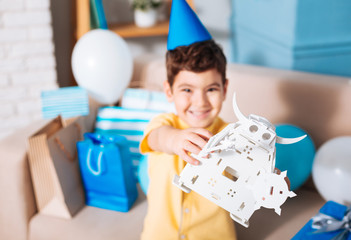 Content with present. The focus being on a white toy robot in the hands of a happy little boy celebrating his birthday and smiling happily