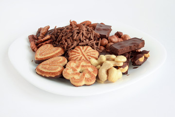 Different sweets and nuts are lying at the white plate.