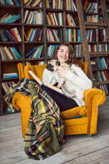 Obraz na płótnie Canvas Happy weekend woman with books reading and funny pug dog. Home cozy library. Relaxed weekend in literature world