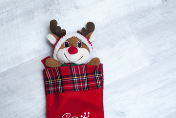 Plush toy reindeer in a Christmas sock on wooden background,