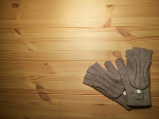 winter gray gloves mittens with a button on a wooden table.