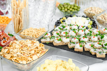 Slices of rye bread wheat bread with herring pieces sprinkled with green onion on a black granite plate. The bacon is milled in a meat grinder on a toast a piece of bread. Buffet snack menu for beer.