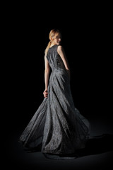 Fototapeta premium Attractive girl in long dress twisting and dancing in dark environment