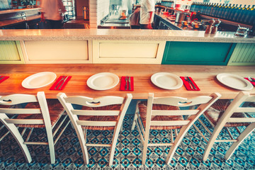 Open Kitchen. Modern and simple cafe interior with wooden furniture - east style mosaic floor, served bar table counter and white chairs. Concept of eating outside and communication. Color filter