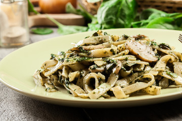 Tagliatelle pasta with spinach and mushrooms on a plate.
