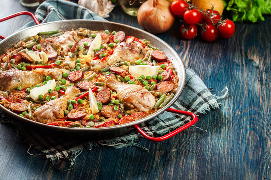 Traditional paella with chicken legs, sausage chorizo and vegetables served in paellera