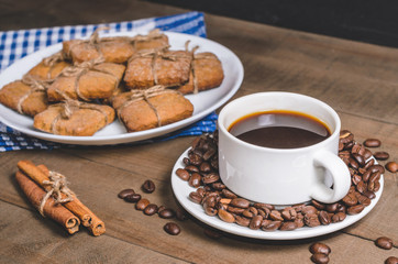 Black coffee in a white cup on a blue napkin and homemade cookies.