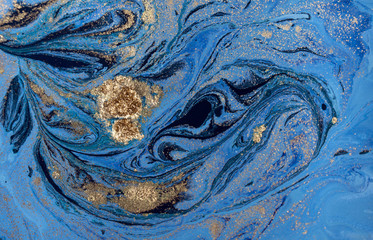 Marbled blue abstract background with golden sequins. Liquid marble ink pattern.
