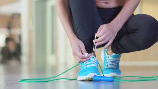 Girl tying shoelaces sneakers and takes a skipping rope