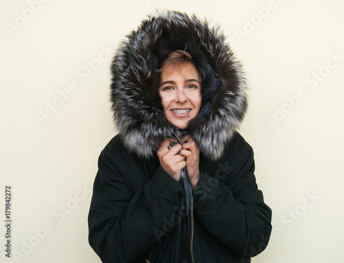 Hipster teen girl posing over wall,wearing warm casual fur