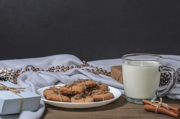 A cup of milk, cinnamon sticks and homemade cookies in a Christmas decor.