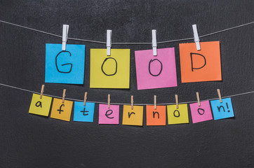 The word "Good afternoon!" on colored stickers on a dark background close up
