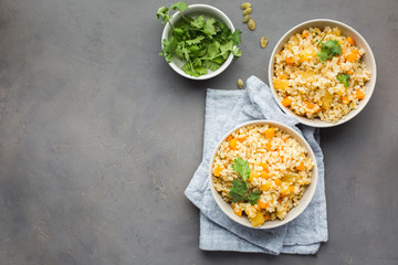 The perfect vegetarian dinner. Bulgur with pumpkin, carrots, spices (ginger, cinnamon, pepper, cardamom), honey and cilantro. A autumn gray concrete background for you.  Flat lay, top view