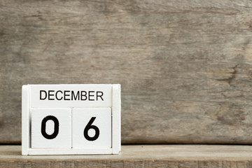 White block calendar present date 6 and month December on wood background