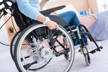 Wheelchair. Paralyzed woman sitting in a wheelchair and wearing a watch and having jeans and...