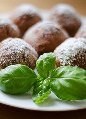 Tasty homemade muffins with powdered sugar decoration on the white plate on the wooden table