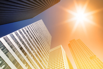 Skyscraper glass facades on a bright sunny day with sunbeams in the blue sky. Modern buildings in Paris business district La Defense. Economy, finances, business activity concept. Bottom up view